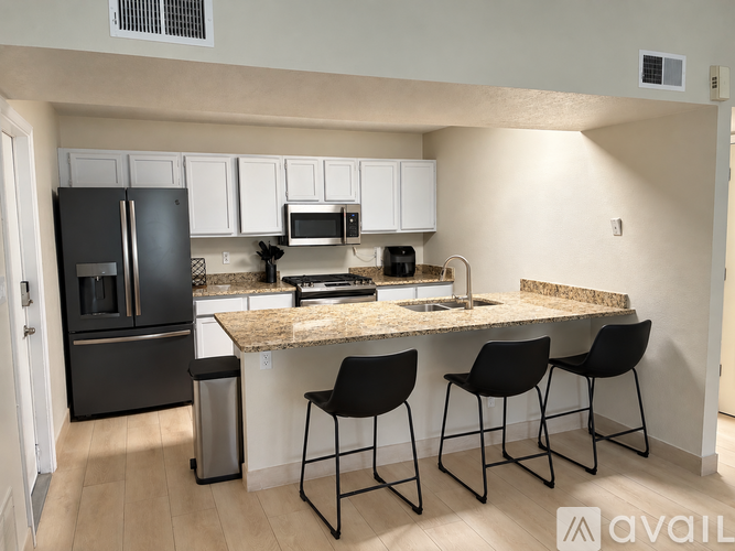 A kitchen with black and white appliances and a granite countertop.