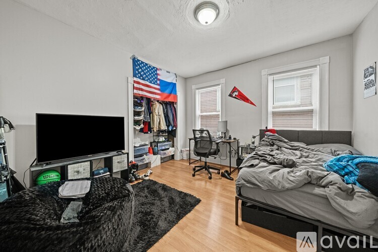 A bedroom with a bed, desk, and a TV.