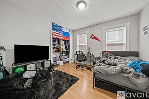 A bedroom with a bed, desk, and a TV.