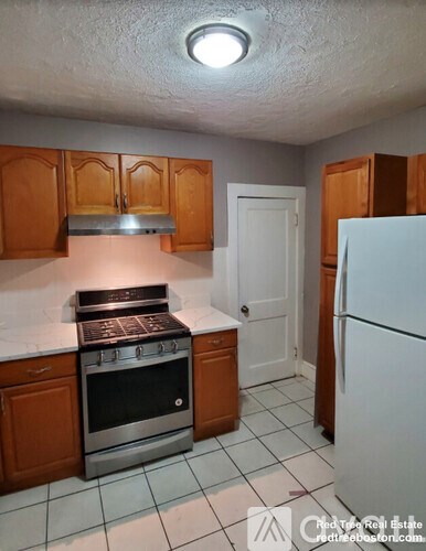 A kitchen with a stove, refrigerator, and cabinets.