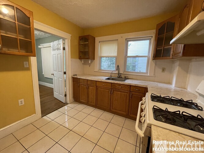 A kitchen with a white gas stove and wooden cabinets.