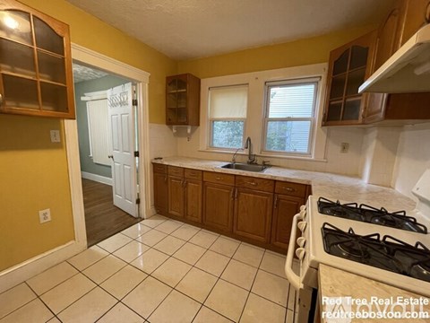 A kitchen with a white gas stove and wooden cabinets.
