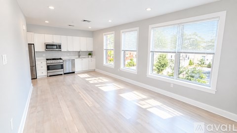 A spacious kitchen with white cabinets and a wooden floor.