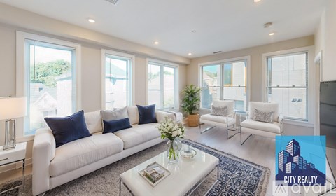 A living room with a white couch, a coffee table, and a large window.