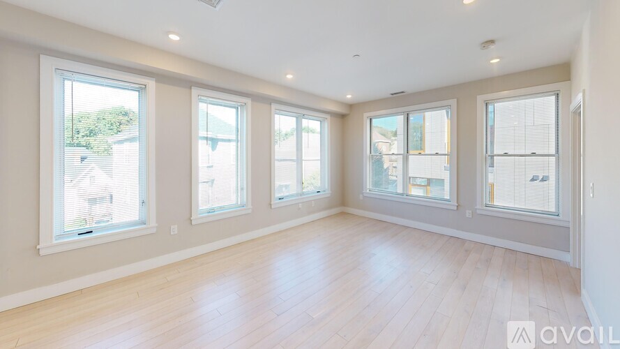 A spacious room with wooden floors and large windows.