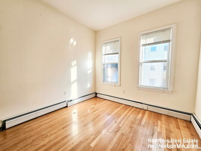 A room with wooden floors and two windows.