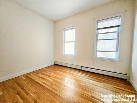 A room with wooden floors and two windows.