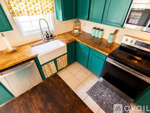 A kitchen with green cabinets and a wooden island.