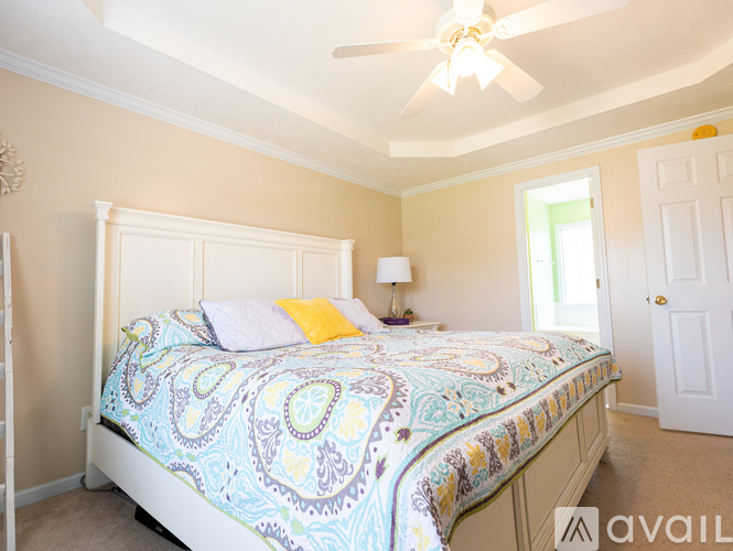 A bedroom with a bed, ceiling fan, and a window.