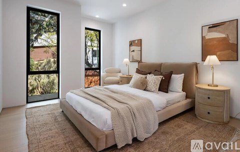 A bedroom with a large bed, a nightstand with a lamp, and a painting on the wall.