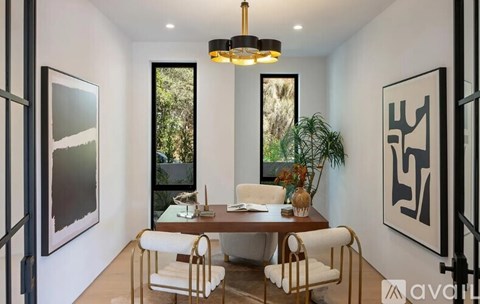 A modern dining room with a table set for two and a view of the backyard.