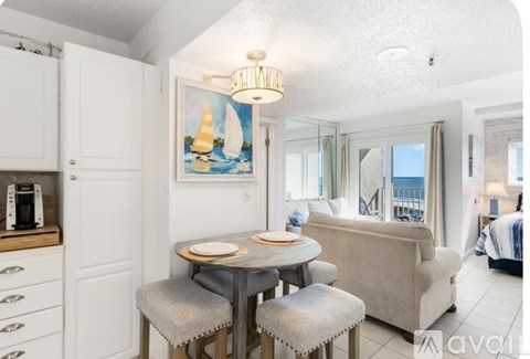 A dining area with a table set for two and a painting of a sailboat on the wall.