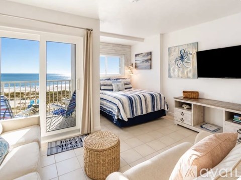 A bedroom with a large bed and a view of the beach through the window.