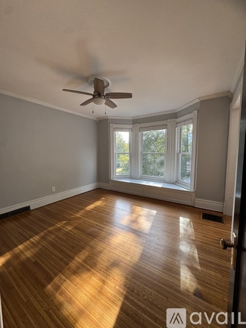 A room with a ceiling fan and a window with a view of trees.
