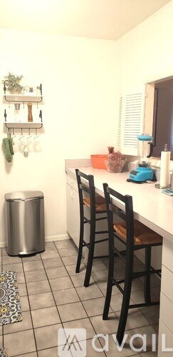 A kitchen with a white counter and a trash can.