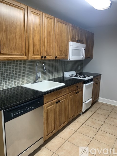 A kitchen with wooden cabinets and black countertops.