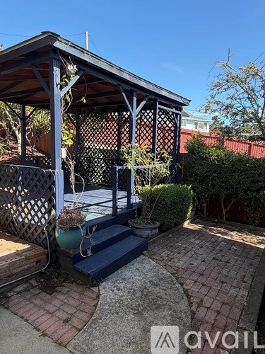 A gazebo with a blue railing and a brick patio.