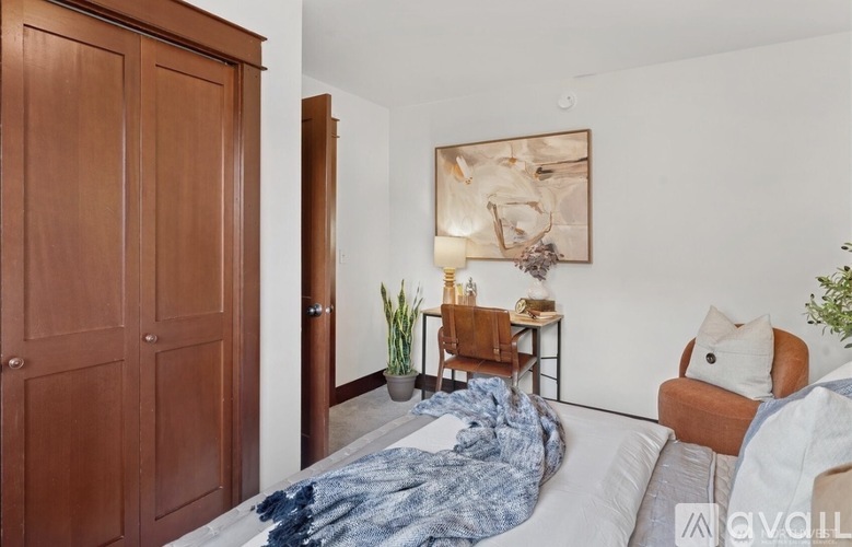 A bedroom with a bed, a chair, and a painting on the wall.