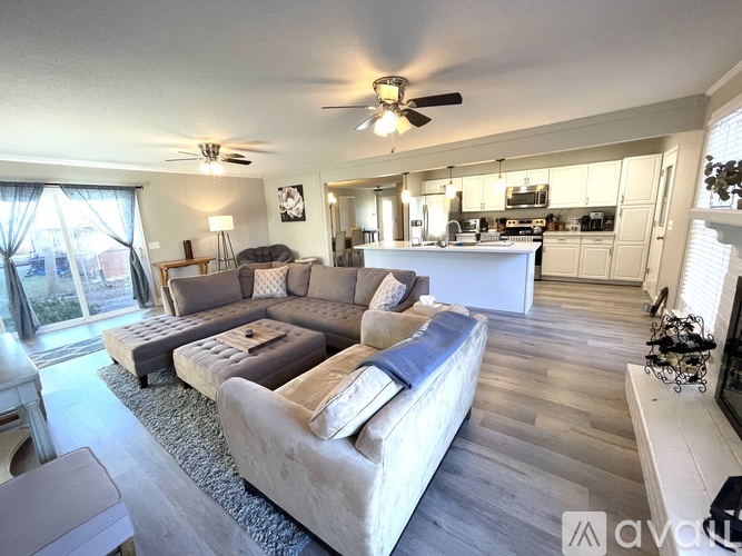 A spacious living room with a large couch and a kitchen area in the background.