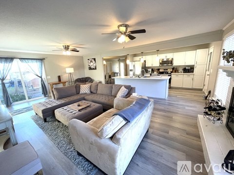 A spacious living room with a large couch and a kitchen area in the background.
