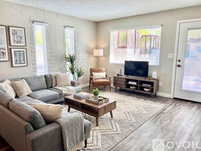 A living room with a grey couch, a wooden coffee table, and a television on a stand.