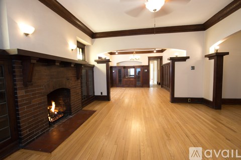 A spacious room with a fireplace and wooden floors.