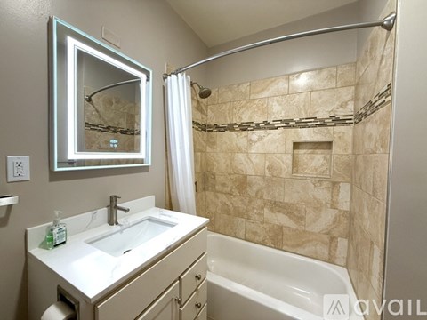 A bathroom with a sink, mirror, and bathtub.