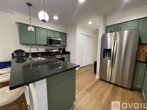 A kitchen with green cabinets and a black countertop.