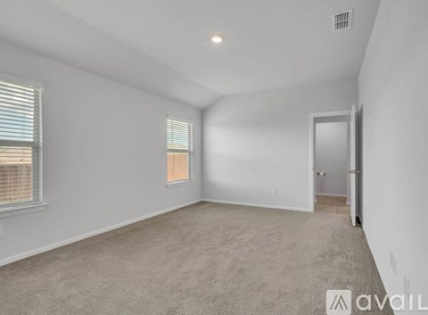 A spacious room with a carpeted floor, a window with blinds, and a door leading to another room.