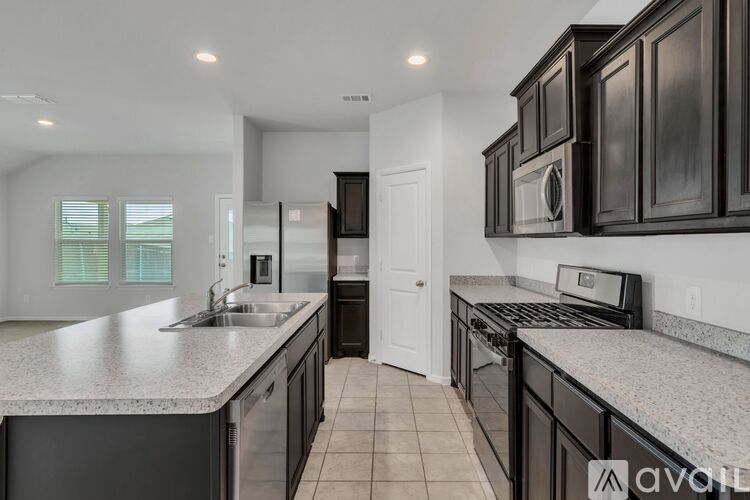 A kitchen with black cabinets and a granite countertop is available.