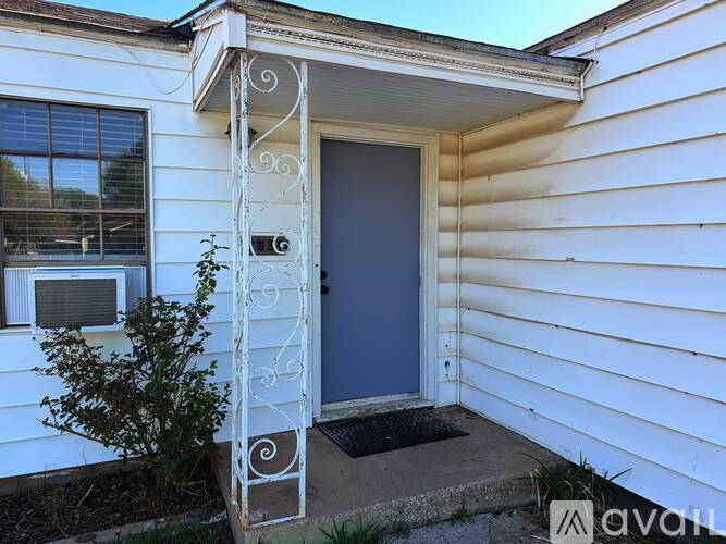 A white house with a grey door and a window with a white frame.