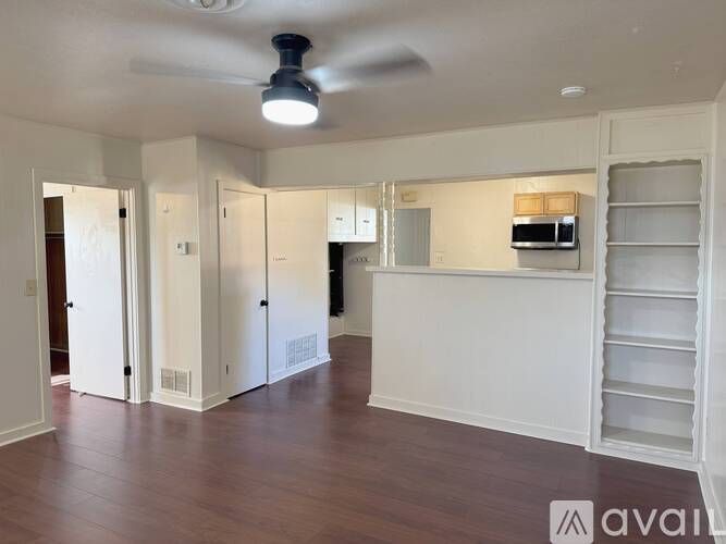 A spacious room with a ceiling fan and a refrigerator in the corner.
