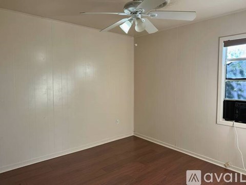A room with a ceiling fan and a window with a view of trees outside.