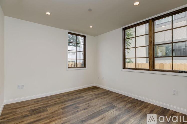A room with wooden flooring and a window with a view of a building outside.