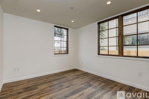 A room with wooden flooring and a window with a view of a building outside.