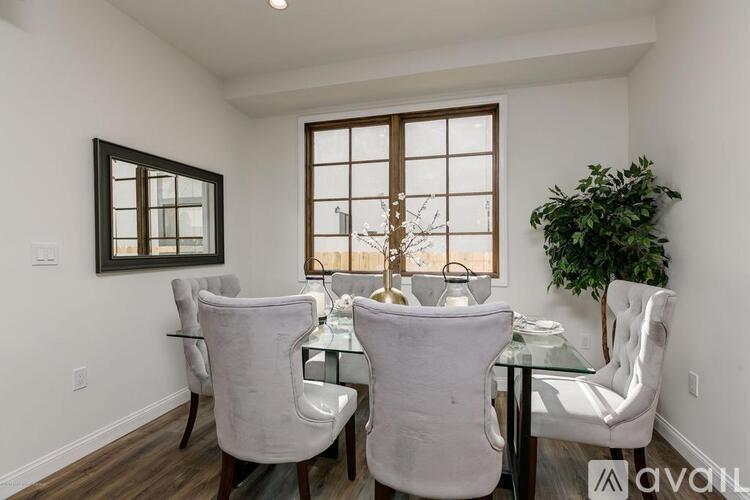 A dining room with white chairs and a glass table.