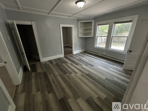 A room with wooden flooring and a window with a view of trees.