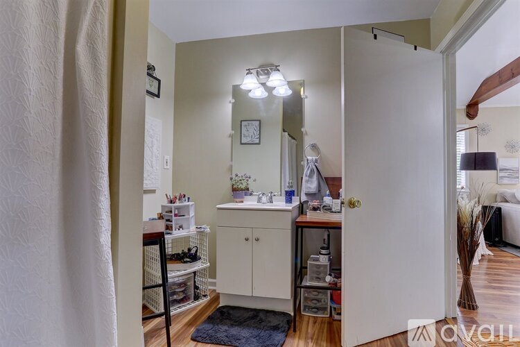 A bathroom with a white cabinet and a mirror above it.