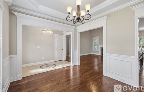 A spacious room with a chandelier and hardwood floors.