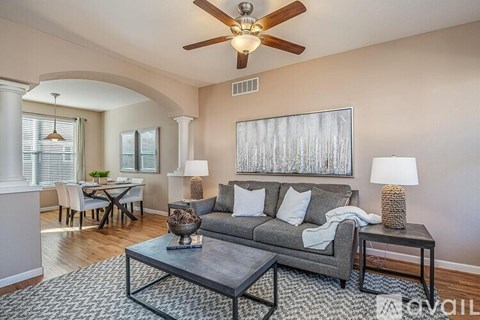 A living room with a grey couch, a coffee table, and a ceiling fan.