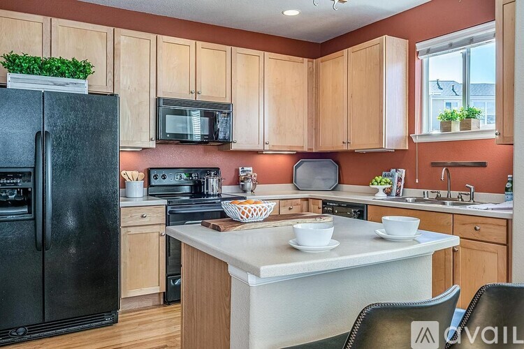 A kitchen with a black fridge, wooden cabinets, and a white countertop.