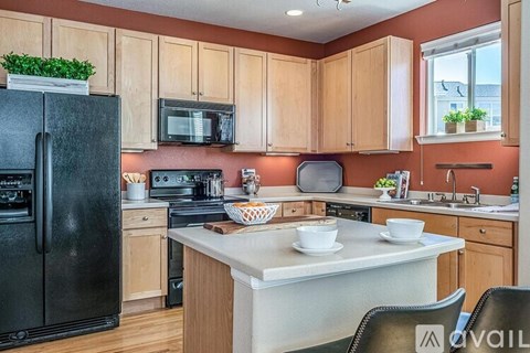 A kitchen with a black fridge, wooden cabinets, and a white countertop.