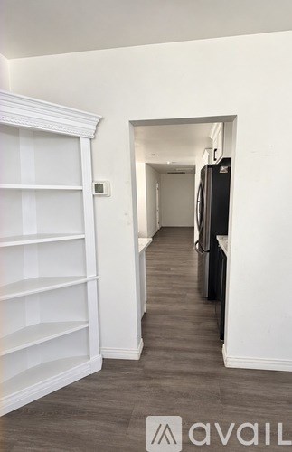 A hallway with a black refrigerator on the right.