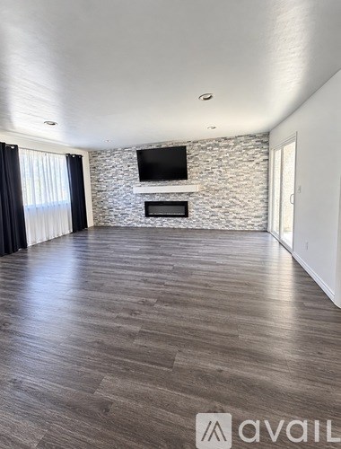 A spacious room with a stone fireplace and a flat-screen TV mounted above it.