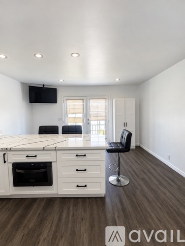 A modern kitchen with white cabinets and a black bar stool.