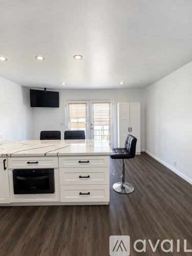 A modern kitchen with white cabinets and a black bar stool.