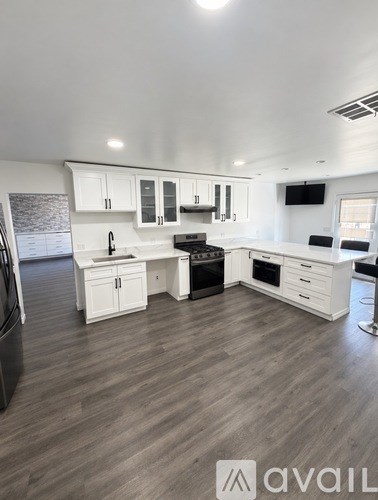 A modern kitchen with white cabinets and a wooden floor.