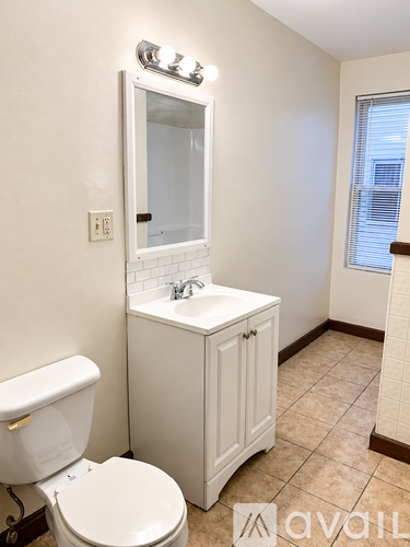 A white toilet sits next to a white sink in a small bathroom.