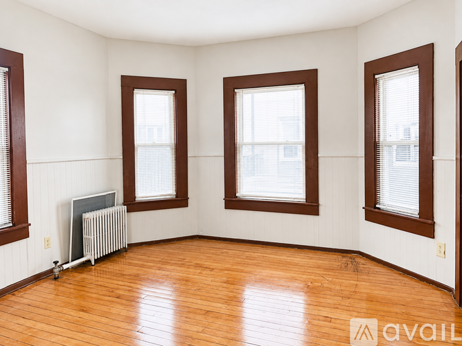 A room with wooden floors and three windows.