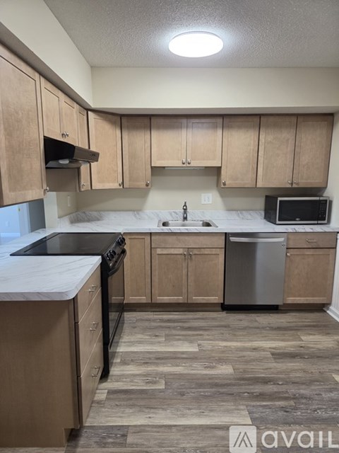 A kitchen with wooden cabinets and a black dishwasher.